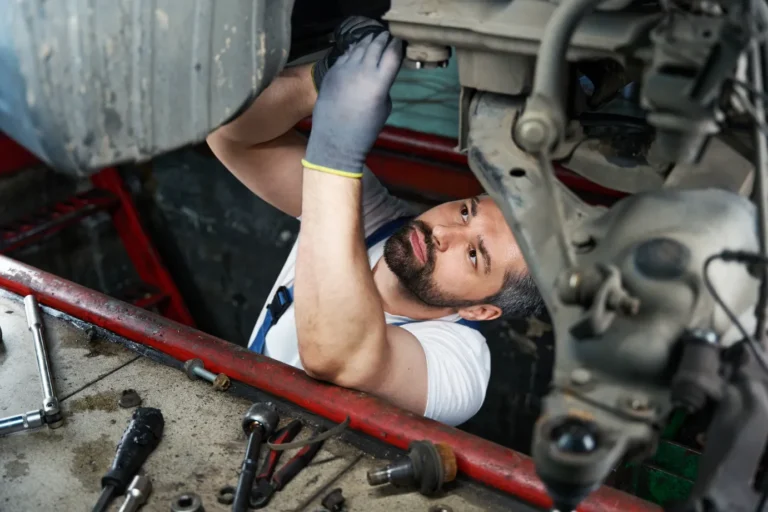 Automotive service technician focusing on fixing under the car suspension.